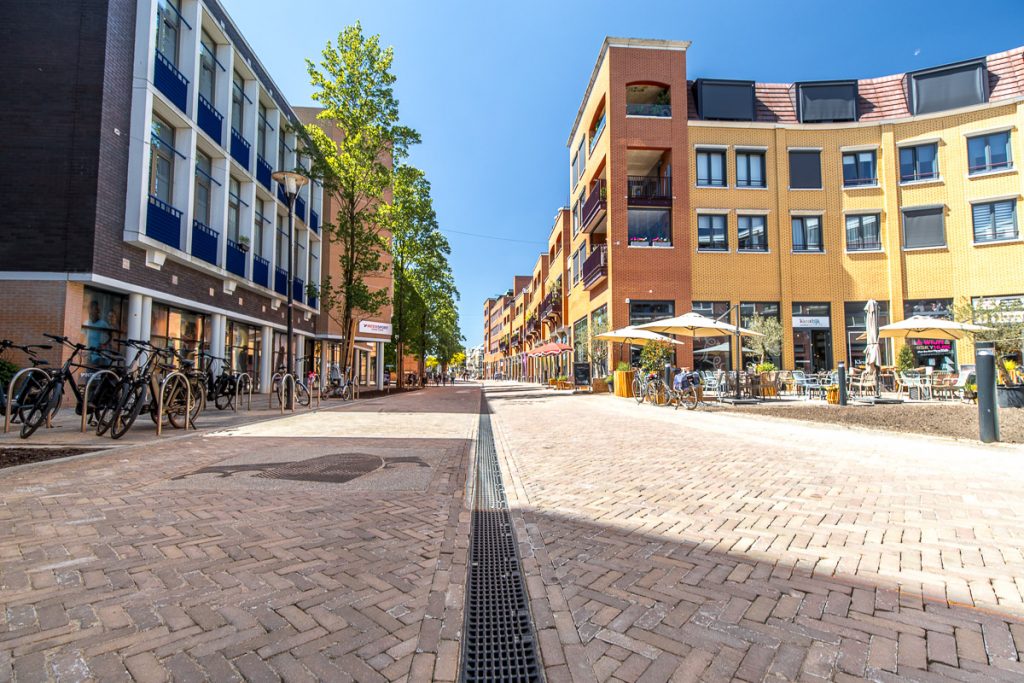 Nieuwe bestrating en lijngoot in de Willem-Alexanderstraat, met winkels en terrassen aan weerszijden.