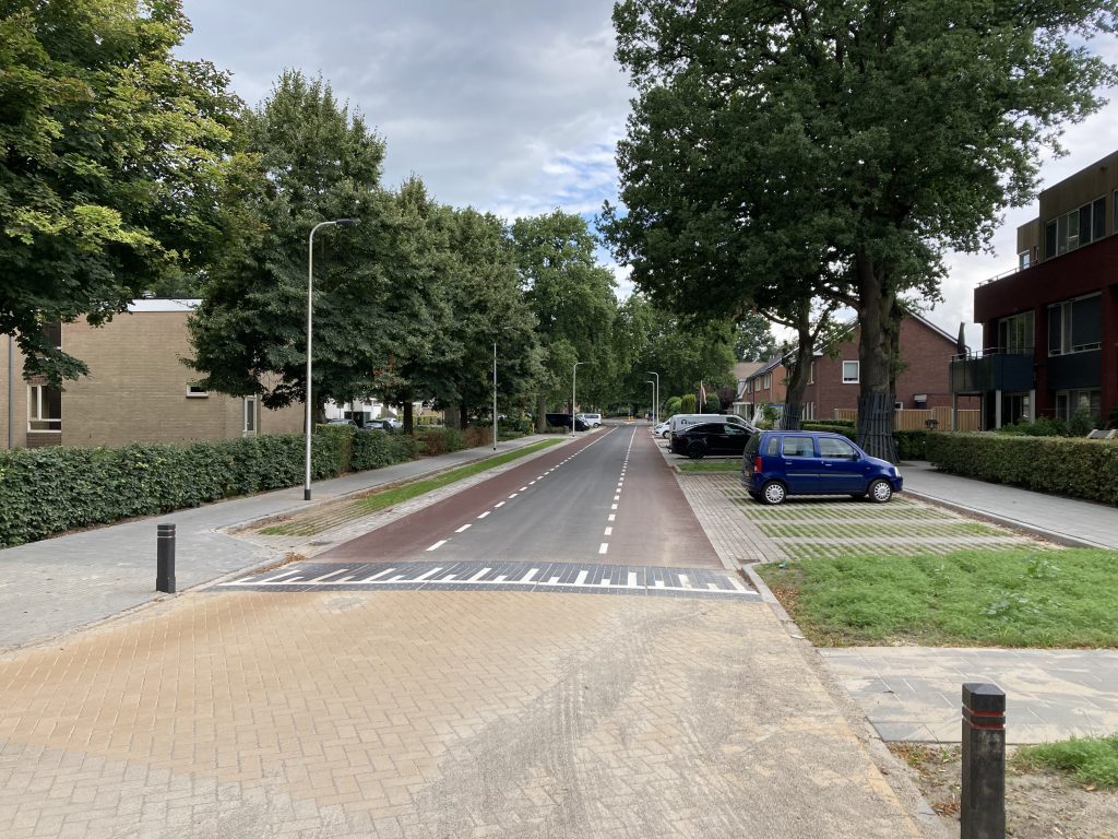 Heringerichte Van Alphenstraat met een vernieuwd wegdek en verkeersdrempel, gescheiden fietsstroken, parkeervakken met grasbetontegels